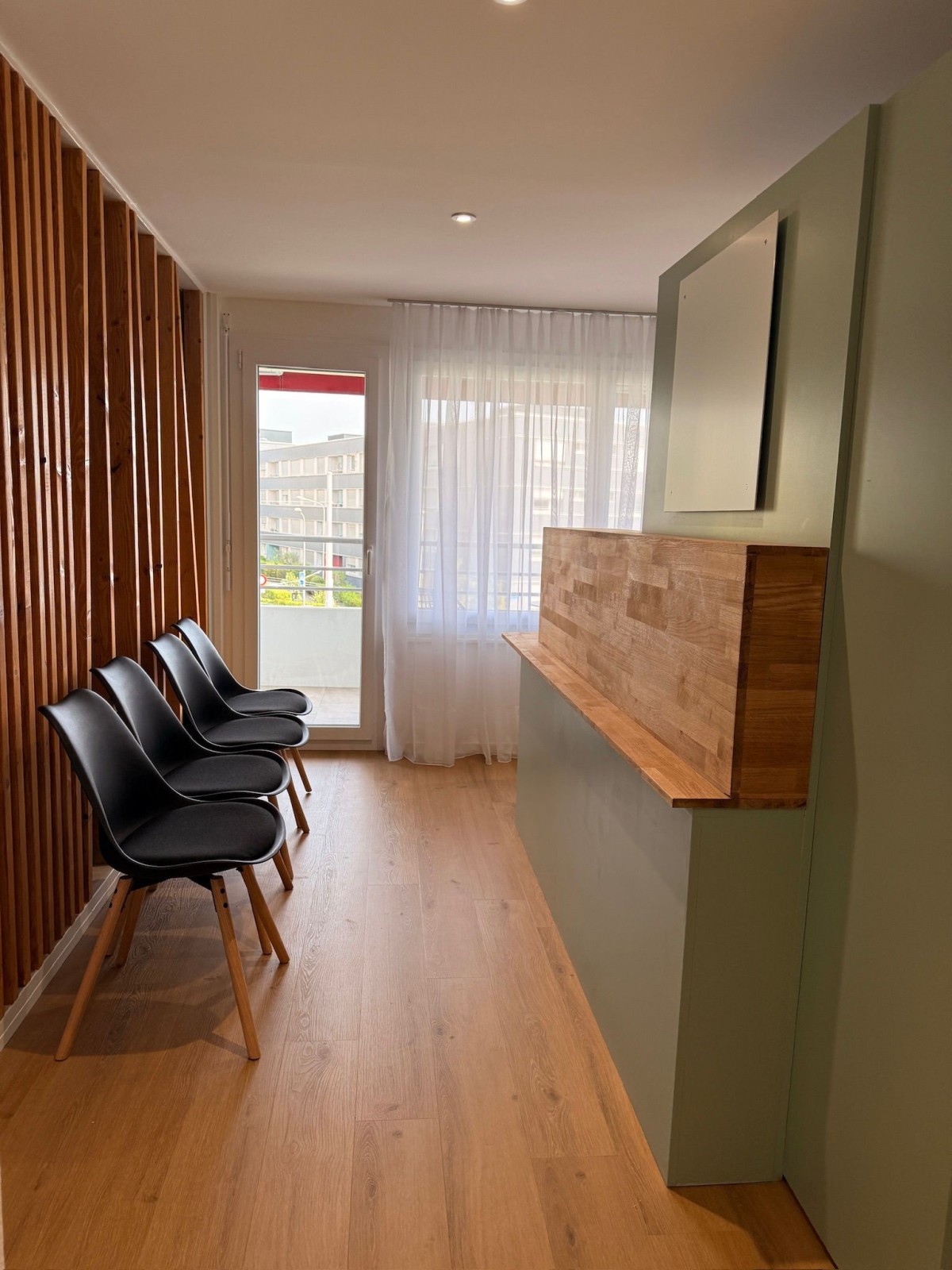 Espace d’accueil du cabinet de Lausanne avec un comptoir en bois et trois chaises.